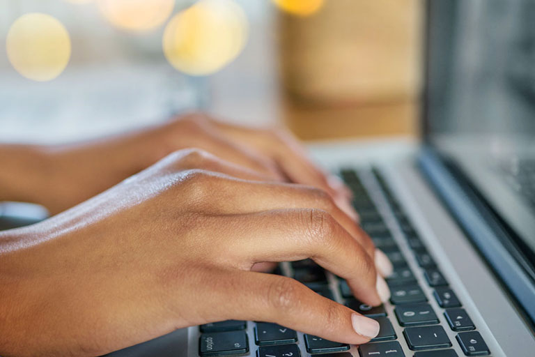 Pair of hands typing on a laptop keyboard